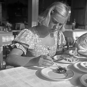 Frau beim Frühstück mit Brötchen und Marmelade in den 1930er Jahren.