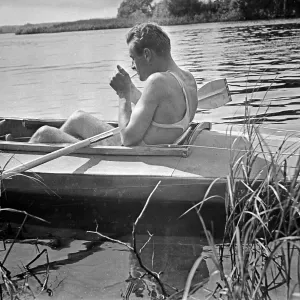 Ein Mann entspannt sich in seinem Klepper Faltboot auf einem See, Deutschland 1930er Jahre.