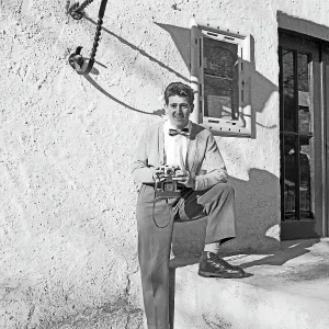 Ein junger Mann mit Kleinbildkamera vor einem Haus in Deutschland 1957.