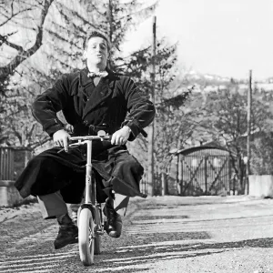 Ein junger Mann fährt mit Mühe auf einem Kinderfahrrad in Deutschland 1956.