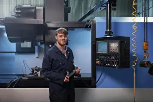 Drucke von Lehrling hält einen U-Bolzenhalter vor einer CNC-Maschine November Drucke: Lehrling hält eine U-förmige Schlaufe vor einer CNC-Maschine.