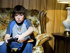 Drucke von Junge mit Videospieleeinheit auf Sofa Mai Drucke: Junge mit Videospielcontroller auf Sofa.