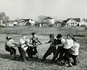 Retro Black And White Photography Drucke: Boys pulling rope on field