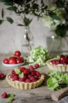 Rustic Food Photography Drucke: A cherry and raspberry tart on a kitchen table