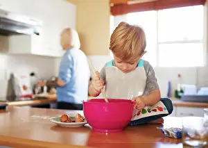 Family Cooking Together Drucke: Child mixing, mom and baking together in kitchen for development