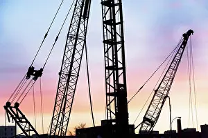 Building Site Equipment Drucke: Construction cranes at sunset