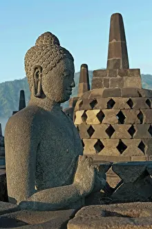 Drucke von Indonesien, Java, Borobudur, Sitzender, Granit-Buddha mit kleinen Stupas im Hintergrund März Drucke: Indonesien, Java, Borobudur, Sitzender Granit-Buddha mit kleinen Stupas im Hintergrund.