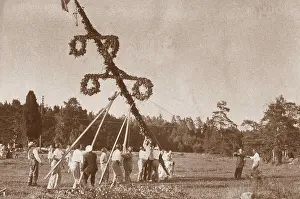 Drucke von Mittsommertradition in den 1930er Jahren. Als Teil der Feierlichkeiten wird ein Maibaum aufgerichtet und hier eine Gruppe von Menschen hebt den Pfosten hoch, bevor sie um ihn herum tanzen beginnen Tanz Drucke: Mittsommertradition in den 1930er Jahren.