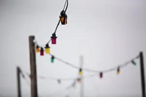 2015 Drucke: Ein buntes Band elektrischer Leuchten gegen einen grauen Himmel.
