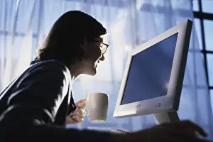 Young Woman Working From Home Drucke: Side profile of a young woman using a computer