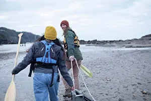 Healthy Lifestyle Outdoor Activities Drucke: Young couple with oars pulling canoe on beach