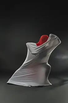 Drucke von Ein abstrakter Figur, der in fließender Gewebe mit einem lebhaften roten Kopfschmuck umhüllt ist, schafft einen auffälligen visuellen Effekt auf einem dunklen Hintergrund Kunstwerke Des Surrealismus Drucke: Ein abstraktes Wesen