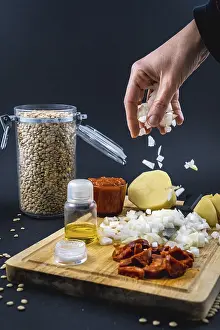 Female Chef In The Kitchen Drucke: Adding onion with a woman's hand to the ingredients