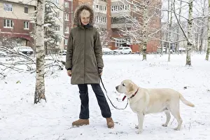 Winter Portrait Drucke: Affection Moment. Outdoor winter scene where woman shares tender moment with pet dog surrounded by snow and bare trees