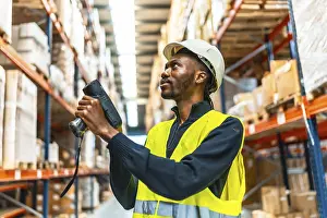 Inventory Management System Drucke: African man using a wireless scan to do inventory in a warehouse