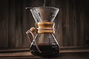 Drucke von Alternative Methode, um leckeres gefärbten Kaffee zuzubereiten. Heißes Wasser in den Glas-Kaffee-Filter gießen. Heißer frischer gebrühter gefärbter Kaffee. Nahkadrastellung Arabica Drucke: Alternative Methode, um leckere gefärbte Kaffee zu machen.