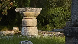 Ancient Olympia Greece Drucke: Ancient stone column in shade surrounded by grass and trees