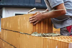 Construction Worker Drucke: Anonymous construction worker on a building site erecting a brick wall