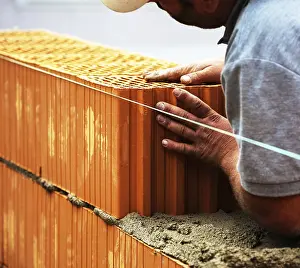 European Construction Work Drucke: Anonymous construction worker on a building site erecting a brick wall