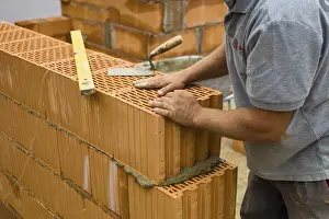 Construction Worker Drucke: Anonymous construction worker on a building site erecting a brick wall