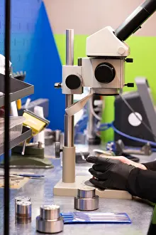 Scientist At Work Drucke: Anonymous scientist in gloves working with a microscope in a production facility