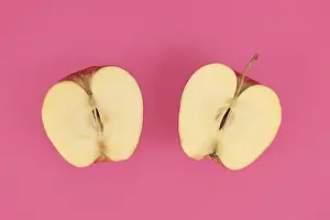 Plain Background Fruits Drucke: Apple cut into half on pink background