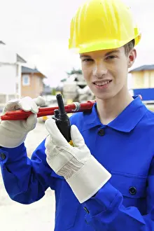 European Construction Work Drucke: An apprentice / trainee. Construction worker on building site with helmet