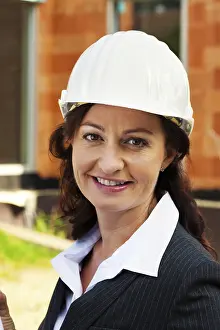 Residential Building Design Drucke: Architect with building plan in front of the shell of a house during construction