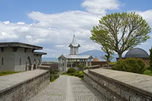 Rabati Fortress Georgia Drucke: Architectural structure with tower and trees under a cloudy sky along a paved path