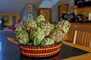 Mediterranean Food Photography Drucke: Artichokes in a basket on a table in the kitchen