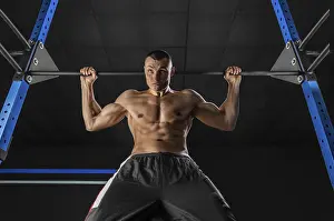 Young Athlete Drucke: The athlete pulls himself on the horizontal bar behind his head