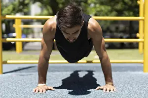 Fitness Exercise Outdoor Drucke: Athletic young man executing a push-up in a park setting