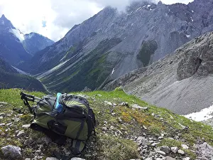 Rocky Mountain View Drucke: Backpack on mountain meadow with a view of steep