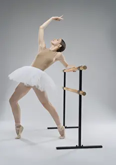 Female Ballet Dancer Pose Drucke: A ballet dancer performs an elegant stretch at the barre