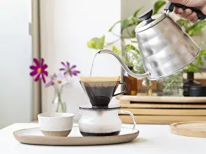 Contemporary Kitchen Setup Drucke: Barista preparing filter coffee using a modern kettle and a ceramic dripper