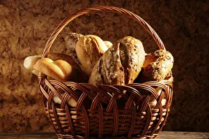 Country Style Baked Goods Drucke: A basket filled with various types of crusty bread against a rustic background