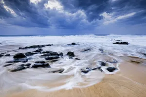 Spanish Coastal Scene Drucke: Beach with stones, waves and clouds