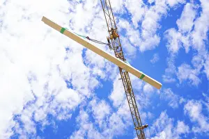 Empty Construction Site Drucke: A beam is hoisted by a crane, sky and clouds in the background