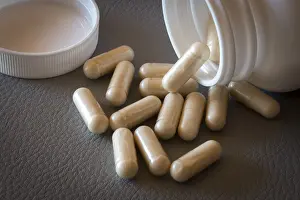 Medical Care Products Drucke: Beige capsules lying on a textured surface from an opened bottle