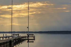Northern Germany Scenery Drucke: A bench on a jetty with the evening sun shining through the clouds