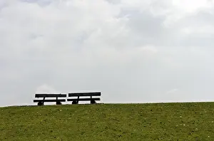 Seating Accommodation Europe Drucke: Two empty benches on a dike crest against the light