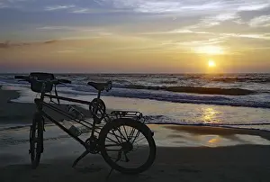Evening Sun Denmark Drucke: Bicycle on the beach in front of the setting sun