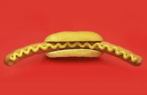 Baked Goods Studio Photo Drucke: Big sausage in a roll on red surface