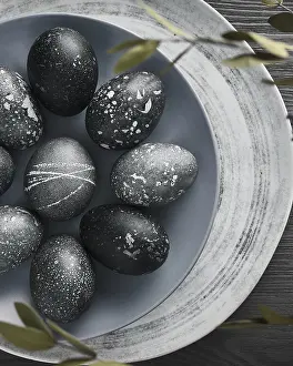 Christian Holiday Traditions Drucke: Black painted eggs for Easter on a blue plate