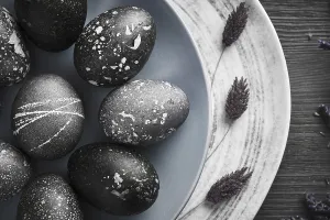 Christian Holiday Traditions Drucke: Black painted eggs for Easter on a blue plate