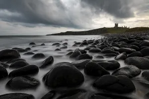 Northumberland Coastline Drucke: Black, round rocks in the surf