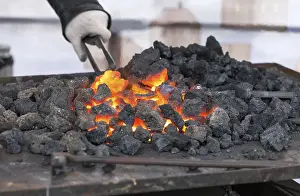 Industrial Workshop Setting Drucke: Blacksmith forges a red-hot iron in the forge