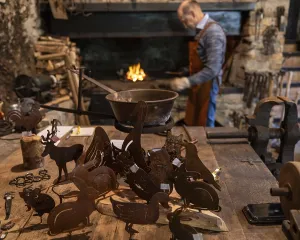 Rustic Wooden Table Scene Drucke: A blacksmith works near a forge in a rustic workshop