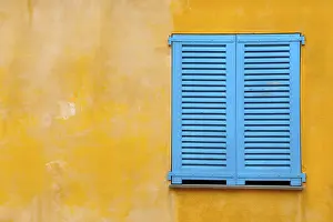 Deserted House Window Drucke: Blue shutter on yellow plaster wall