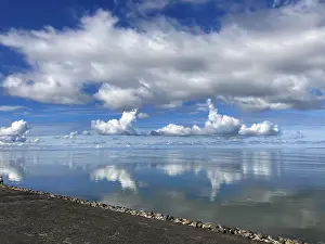 Wattenmeer Drucke: Das blaue Himmel mit Wolken wird im Meer widergespiegelt.